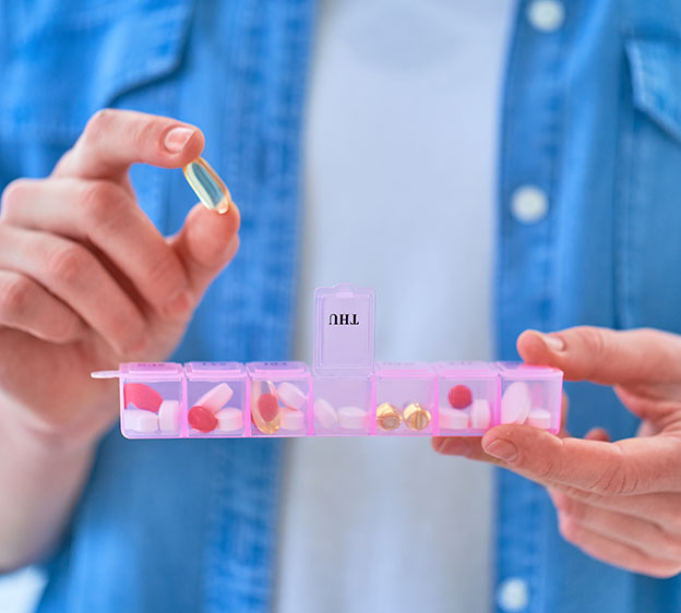 Close-up photo of a woman’s hands holding a pill box