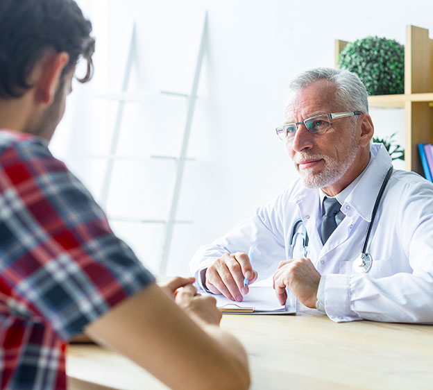 Doctor holding a pen and listening to a patient closely