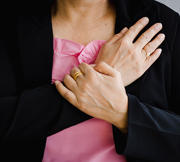 A woman holding her chest with her arms crossed against her body