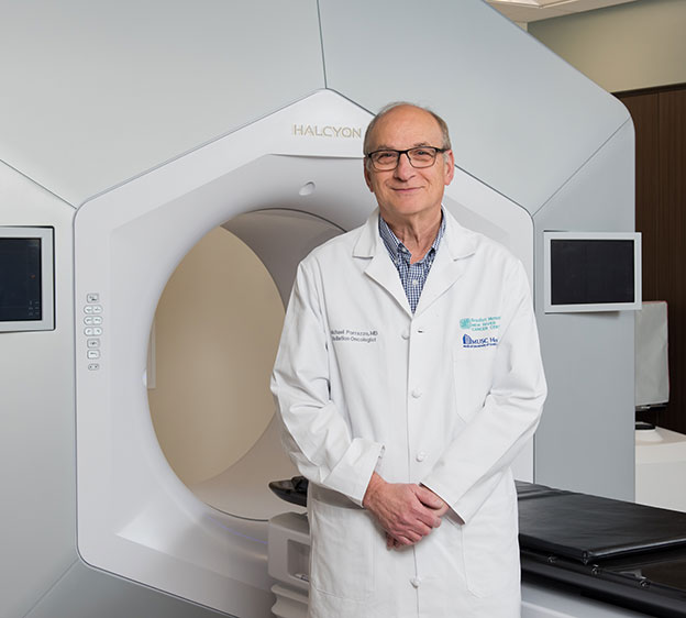 Dr. Michael Porrazzo, a radiation therapist, standing in front of a piece of imaging equipment