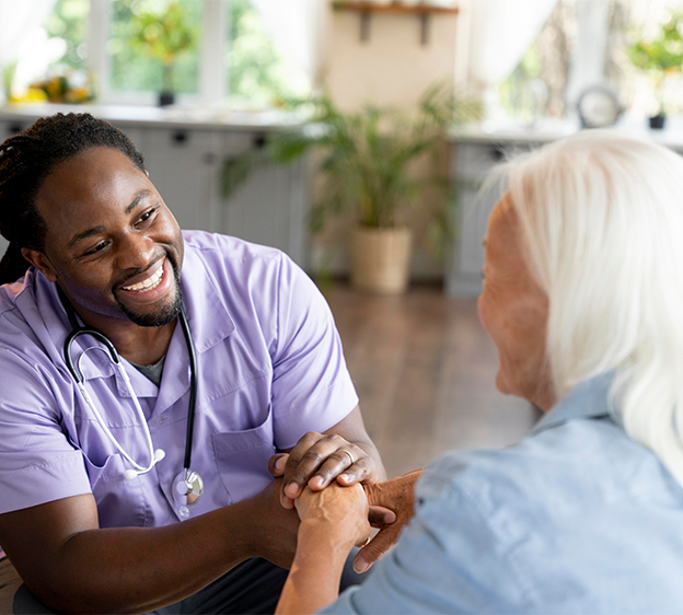 Social worker holding hands and smiling while caring for an older woman