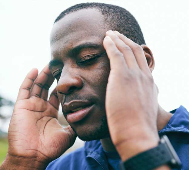 Man places fingers on the sides of his temples and closes his eyes