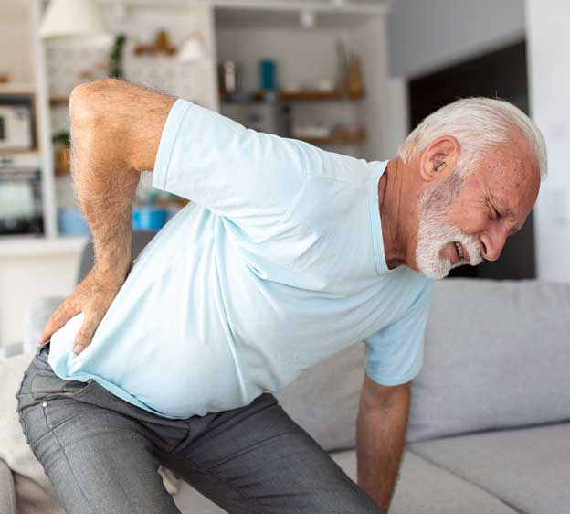 Older adult man touching his back and appearing to suffer from back pain