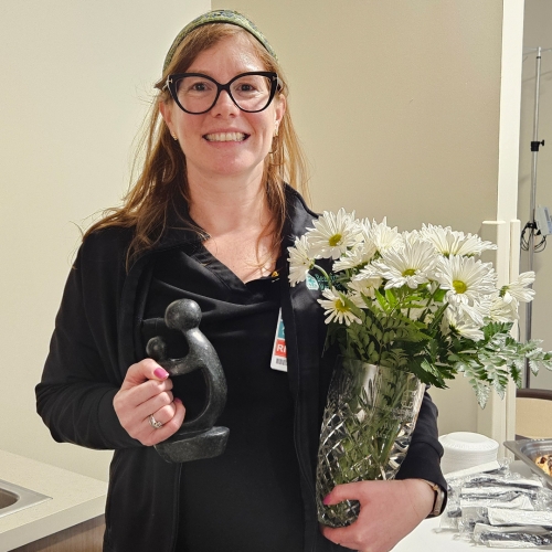 Annie Loughlin RN, BSN with her DAISY award and a vase of daisies