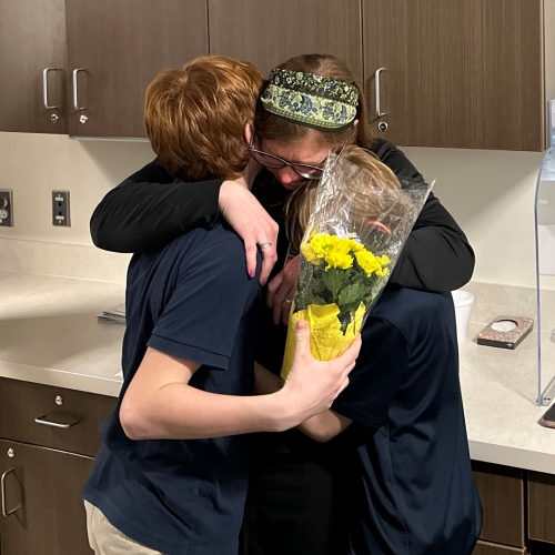 Annie Loughlin, RN, BSN, hugs her kids at her surprise DAISY award ceremony