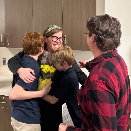 Annie Loughlin, RN, BSN is embraced and hugged by her two sons and her husband