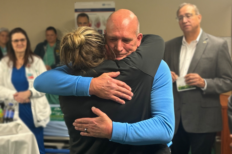 Mike Olmstead hugs Nancy Morrison, RN, BSN, during a surprise DAISY award ceremony