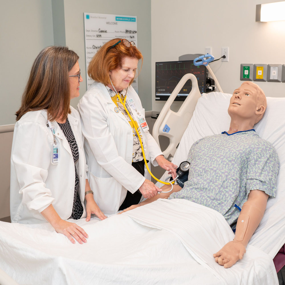 Nurse taking blood pressure measurement on patient simulation manikin