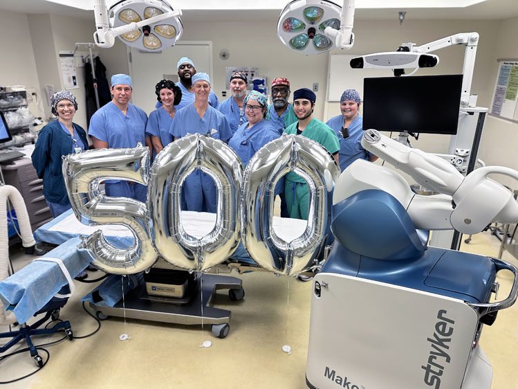 Surgical team poses with balloons marking 500th robotic joint replacement surgery