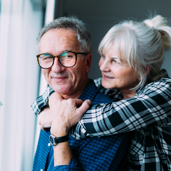 Man and wife hugging in front of a bright window