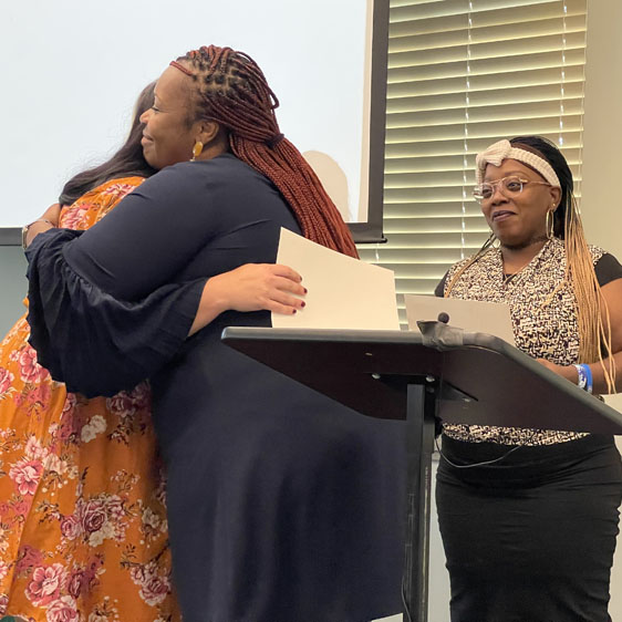 Two women hug after a PATH graduate receives certification