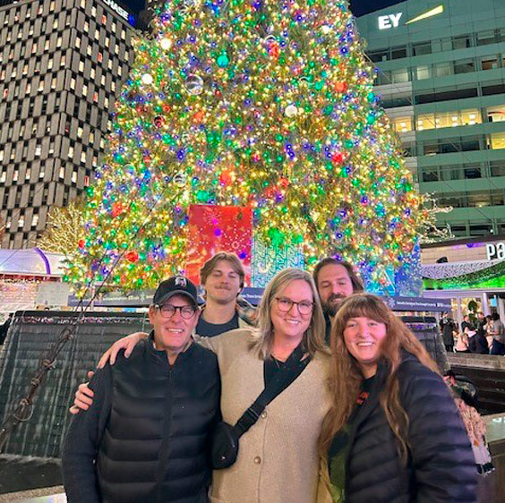 Dr. John Krcmarik, his wife, and their three children in front of a large, lit up Christmas tree outdoors