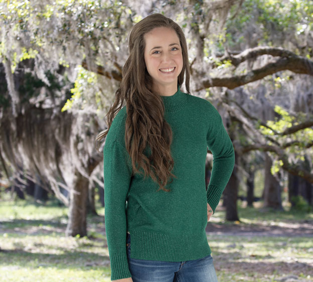 Nurse Practitioner Taylor Robinson wearing a green sweater and standing in front of Spanish moss.