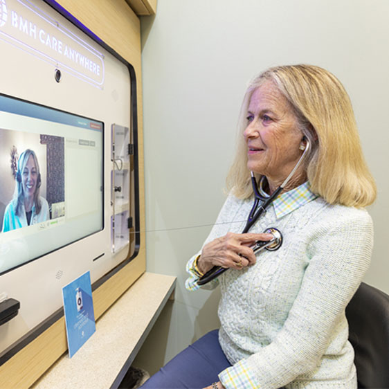 A woman in a telehealth visit holds a stethoscope