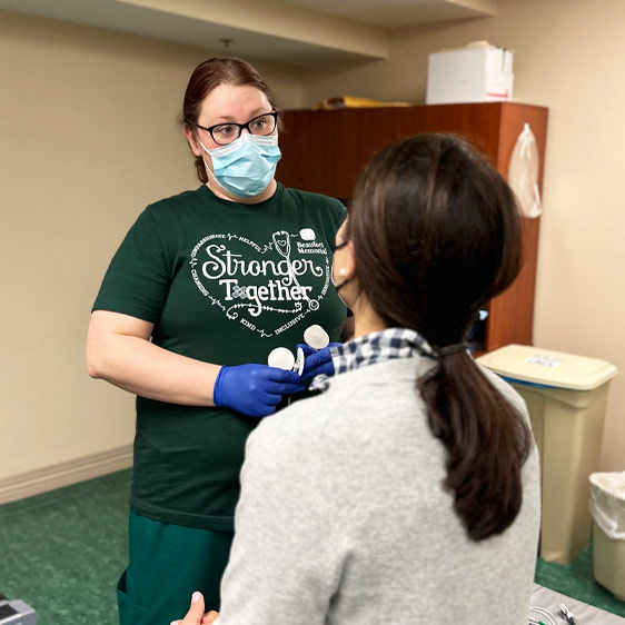 Jamie Harmon speaks with a patient sitting on an exam table.