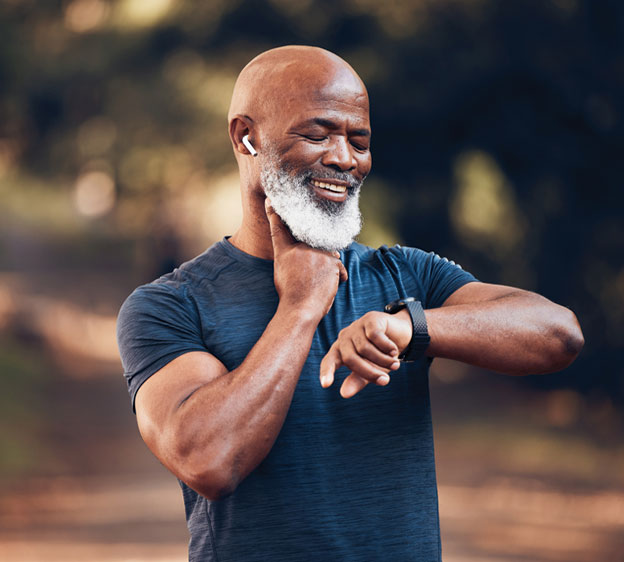 An older Black man with a beard checks his heart rate while looking at his watch.