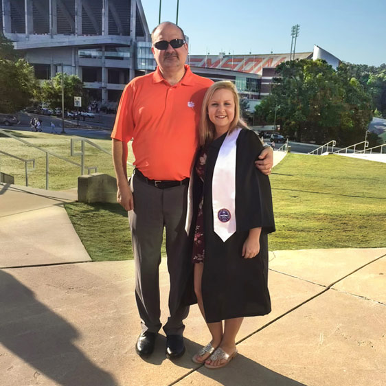 Eric Gearhart with his daughter Ashley at her graduation from Clemson University. Ashley is wearing a graduation gown and sash.