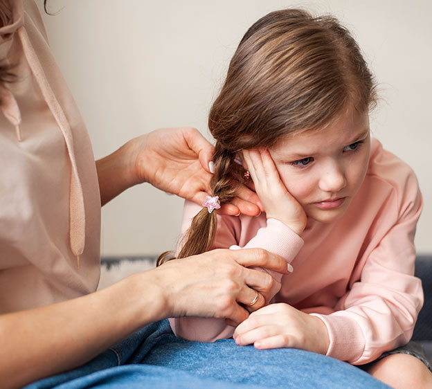 A little girl holding her ear with her hand and a guardian reaching for the child&rsquo;s ear.