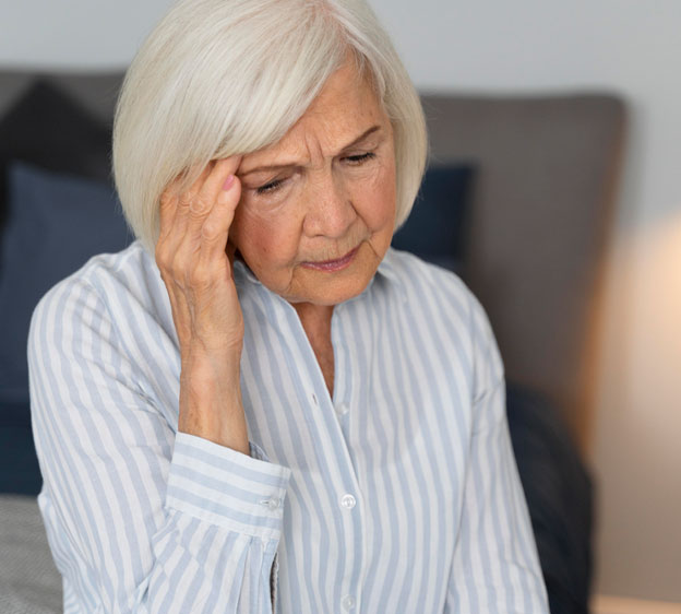 Older woman looking confused and sitting on a bed