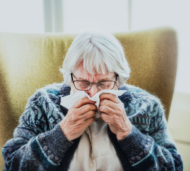 Older woman with allergies sneezing into a handkerchief