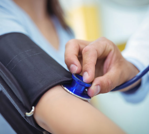 A woman wears a blood pressure cuff as a healthcare provider takes her blood pressure.