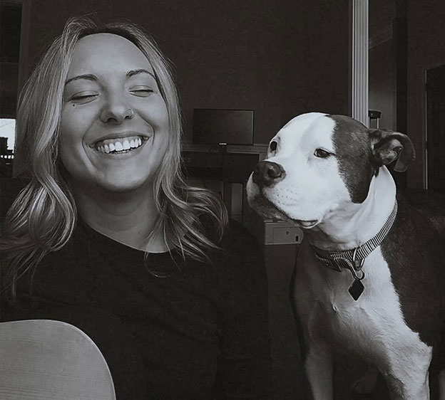 A black and white photo of Samantha Bruns, BSW, social worker at Beaufort Memorial, smiling for a selfie with her dog, Zella