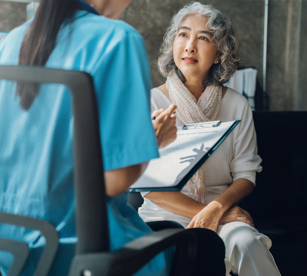 An older woman speaks with a care navigator holding a clipboard.