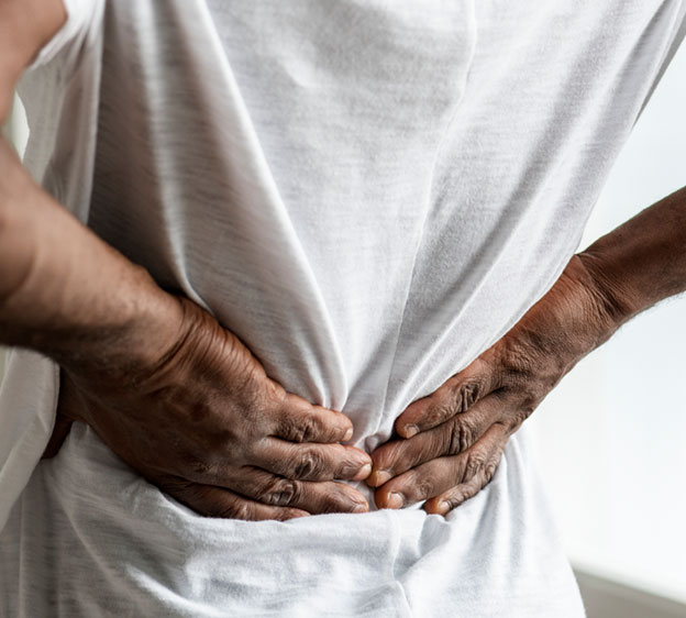 Man wearing a white t-shirt holding his lower back in pain