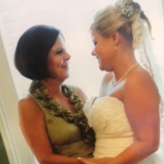 Carol Thames and Chelsey Bates photographed at Chesley's wedding, with Chelsey in her wedding dress and the two women looking at each other and smiling