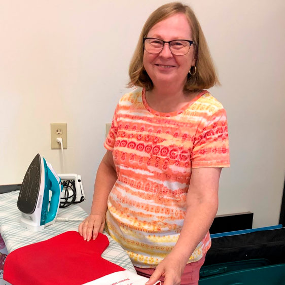 Sea Island Quilters Guild Outreach Committee Chair Brenda Lucas standing next to a table with an iron on the table