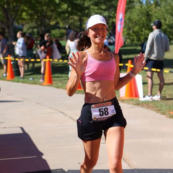 Roxanne Davis wearing running clothes and holding her arms up while participating in a marathon