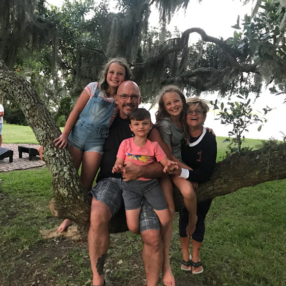 Beaufort Memorial Pharmacy Services Director Tim McCall sits on a limb of a Spanish oak with two young girls and two young boys.