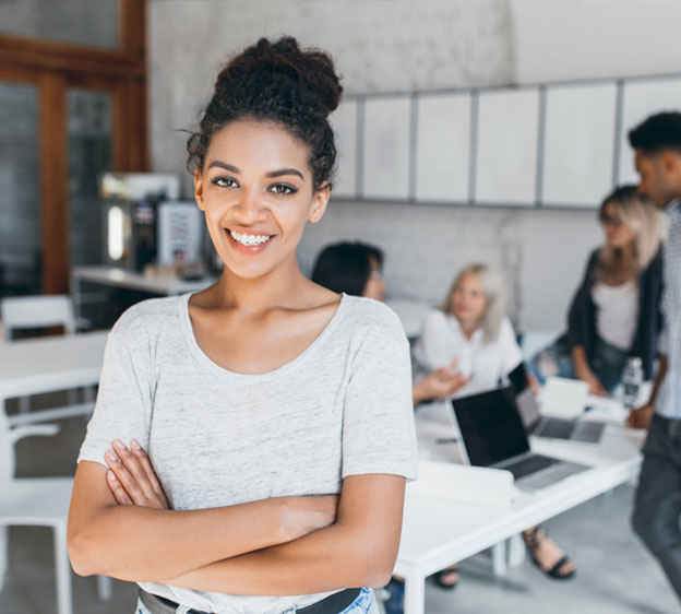 Young Black woman smiling surrounded by co-workers in an office