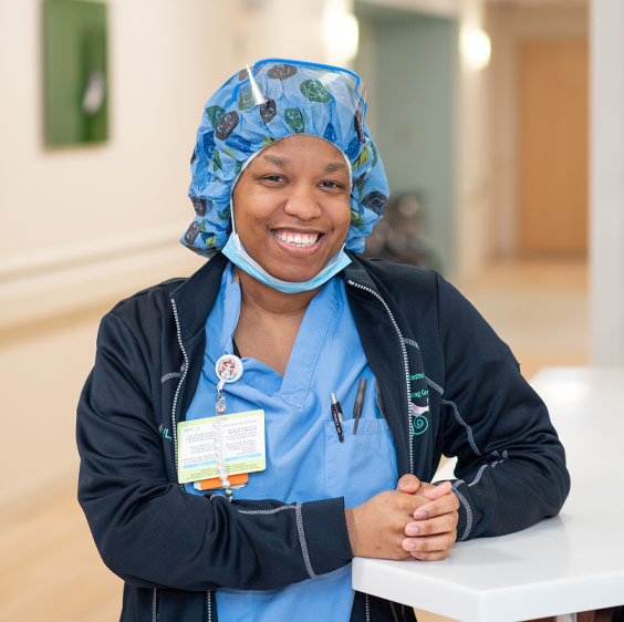 A staged photo of TeTe Lundy who smiles at the camera and wears surgical scrubs