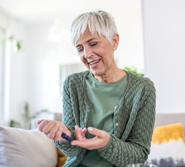 A woman in a green sweater tests her insulin levels.