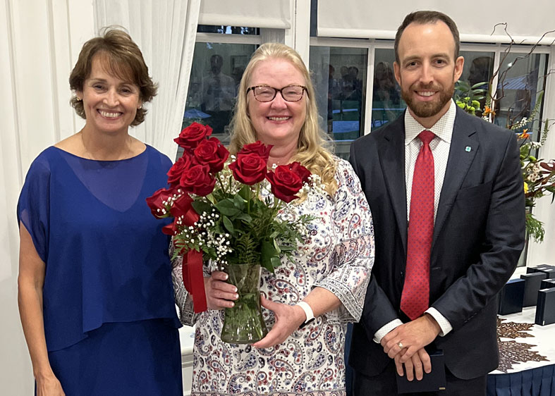 Julie Schott holds flowers and poses with Karen Carroll and Russell Baxley