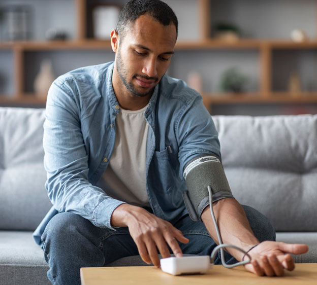 Man checks his blood pressure while sitting on a couch