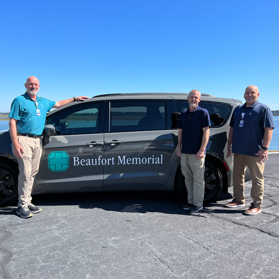 Three Beaufort Memorial volunteers stand next to the Beaufort Memorial transportation van