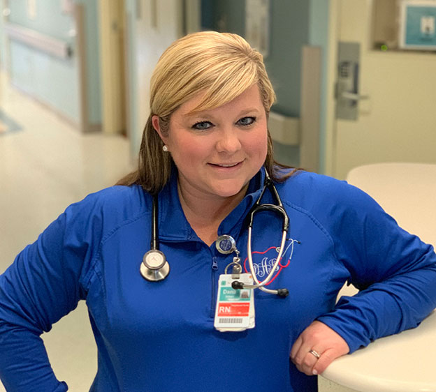 A blond-haired nurse named Dana Aiken smiling for a close up photograph