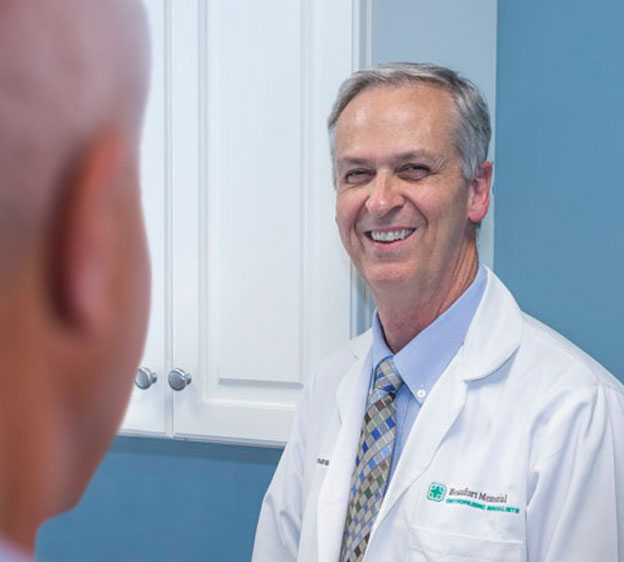 Dr. Kevin Jones of Beaufort Memorial smiling at the camera with a figure of a man in the foreground.