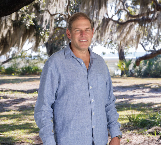 Dr. John Krcmarik standing in front of Spanish Moss and smiling for a photograph.