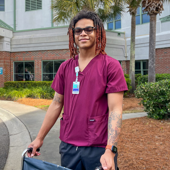 Jaysun Puryear smiling and wearing dark red scrubs