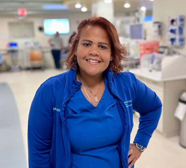 Meridith Godinez Carrillo smiling for the camera and wearing blue hospital scrubs