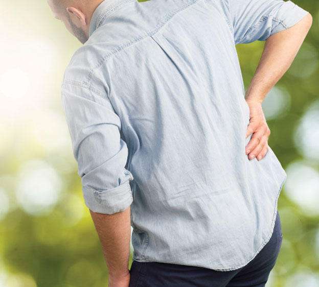 Older adult man holding his lower back and bent over slightly