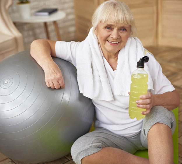 Older woman sitting next to an exercise ball