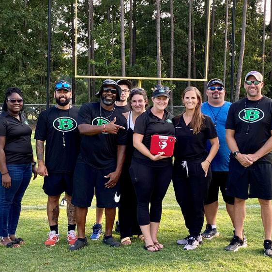 Bluffton Bulldogs football and cheer coaches pose with AED