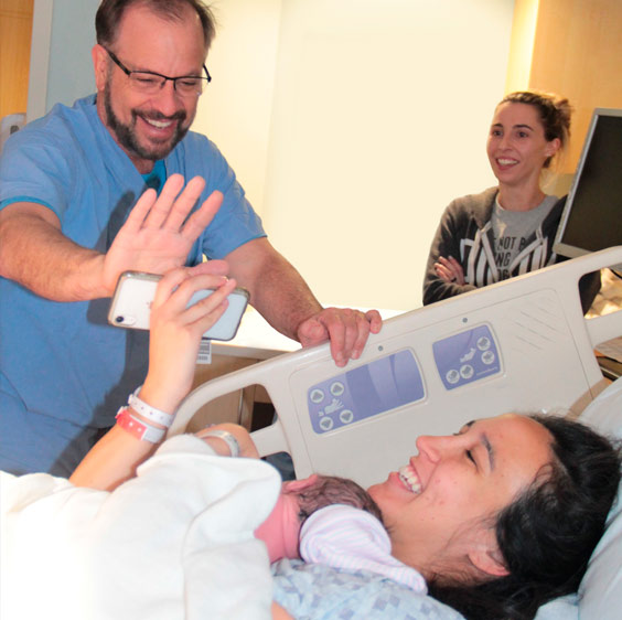 Dr. Gregory Miller digitally high-fiving Ted Sr. and Claire Hardee holding their newborn