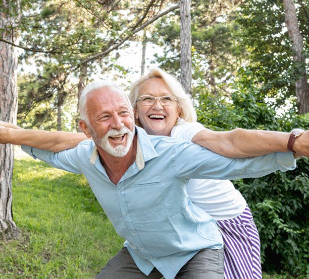 An older man and his wife acting playful outdoors