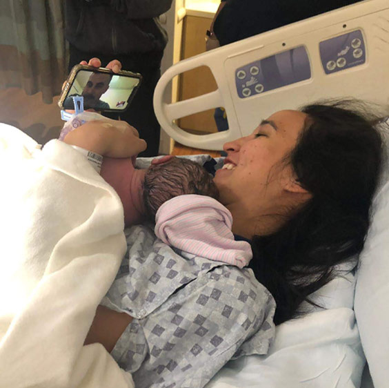 Claire Hardee holding her newborn while on a video call with her husband Ted