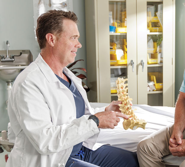 Dr. Andrew Castro shows a patient how disc replacement surgery works using a model of a spine.